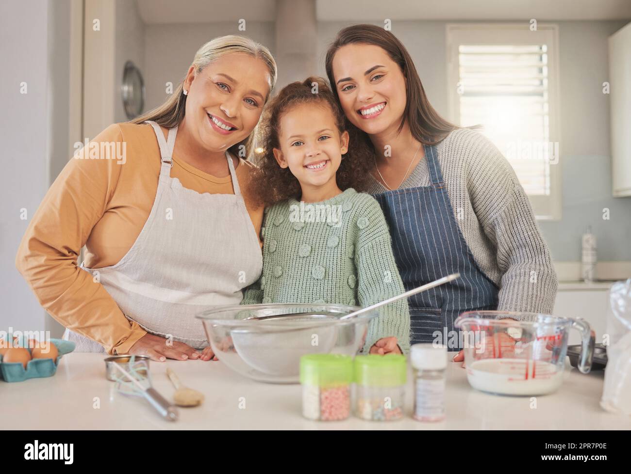 Wenn Sie sich nach etwas Süßem sehnen, dann schlagen Sie es auf. Aufnahme eines kleinen Mädchens, das mit ihrer Mutter und Großmutter zu Hause backt. Stockfoto