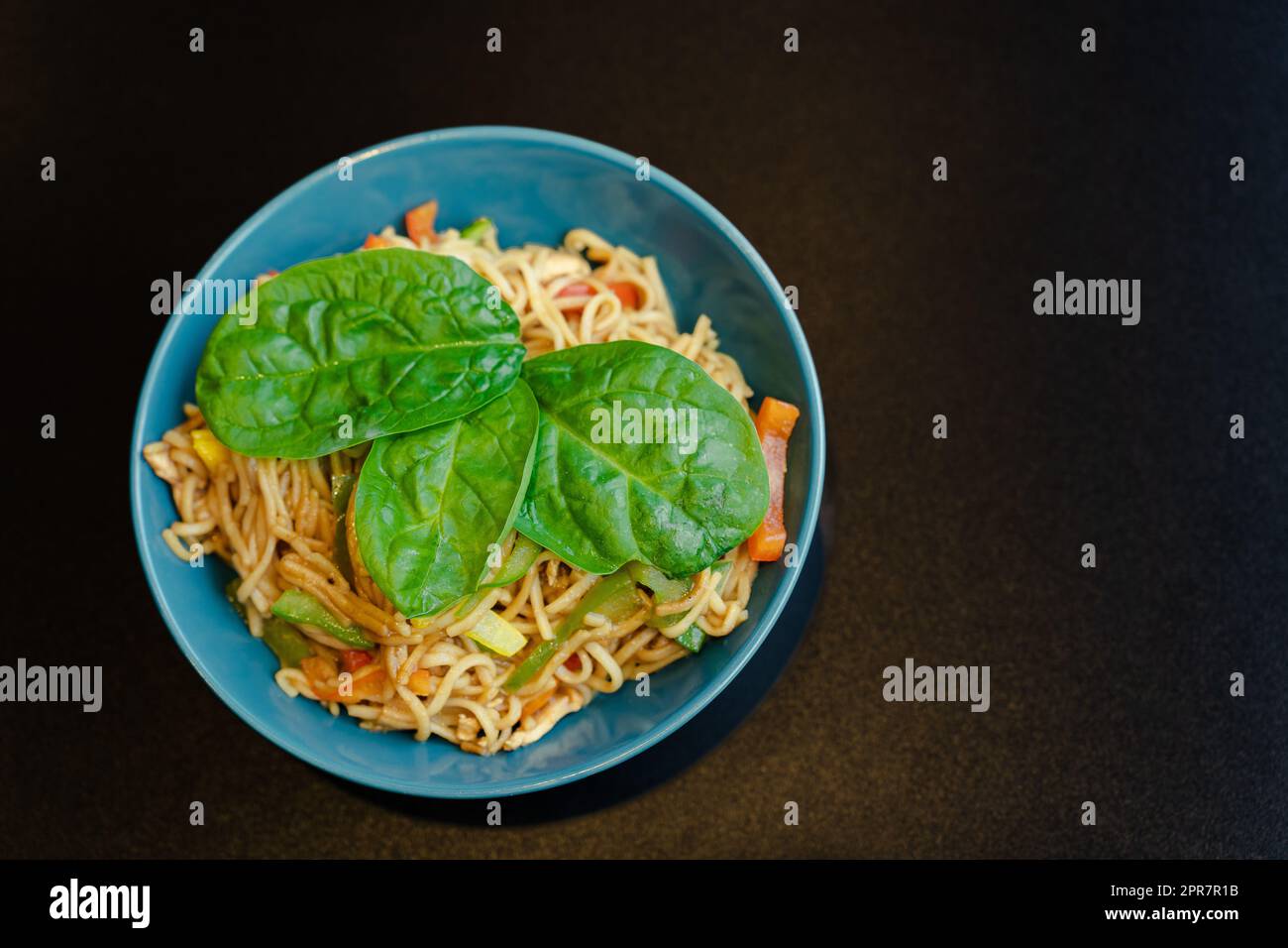 Draufsicht einer Spaghetti-Platte mit Gemüse und Basilikumblättern Stockfoto