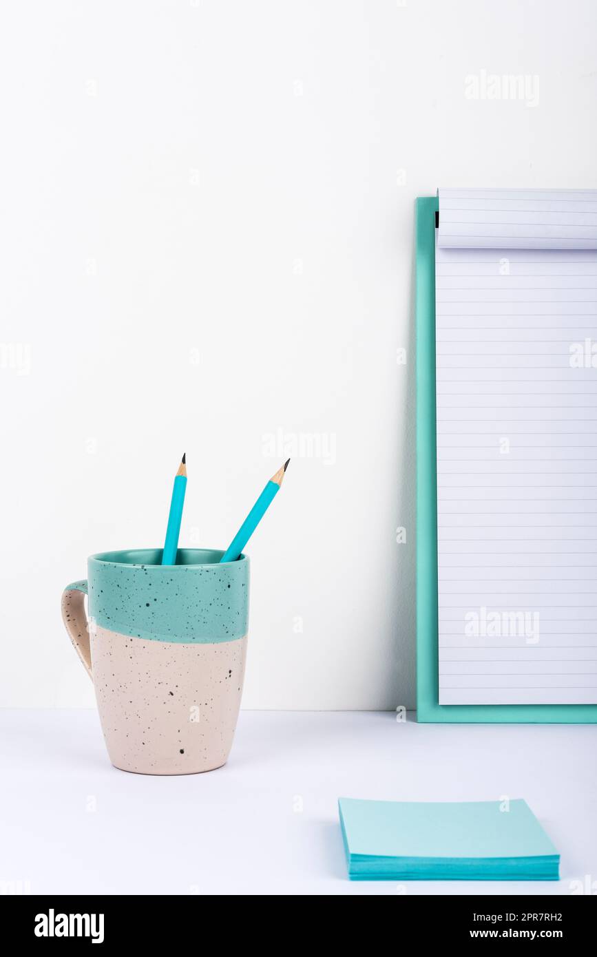 Becher Mit Zwei Bleistiften Auf Dem Schreibtisch Mit Klemmbrett Mit Wichtigen Nachrichten Und Notizen. Tasse Mit Stiften Auf Dem Tisch, Mit Memos Mit Grausamer Ankündigung. Stockfoto
