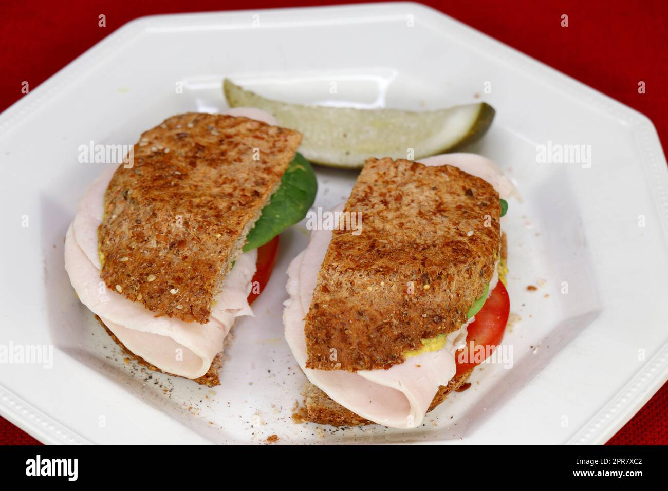 Truthahn-Sandwich mit Tomaten-Spinat und Senf auf Brot mit einer Gurke Stockfoto