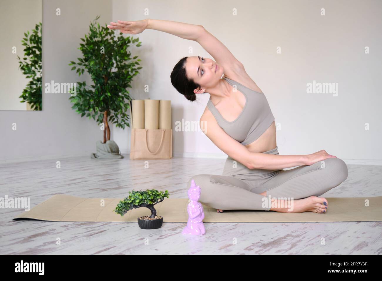 Eine junge Frau mit einem athletischen Körper macht phineas auf einer Yogamatte. Stockfoto