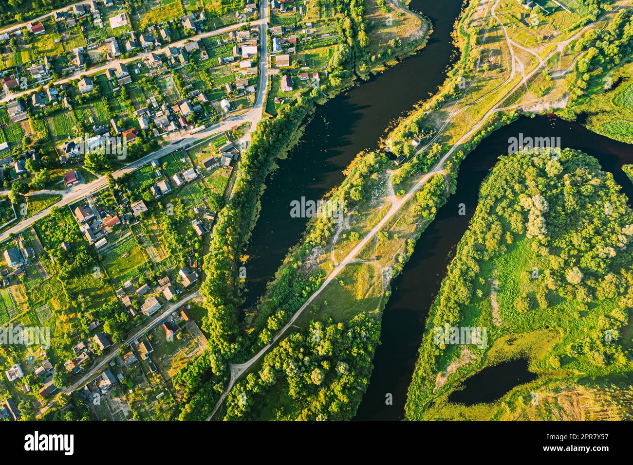 Luftaufnahme Des Calm River And Village In Weißrussland, Europa. Grüne Waldlandschaft Am Sonnigen Sommerabend. Blick Von Oben Auf Die Wunderschöne Europäische Natur Von High Attitude. Drohnenansicht. Vogelperspektive Stockfoto