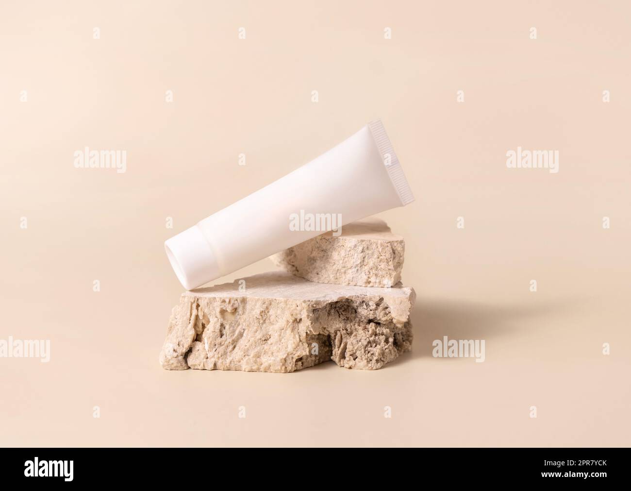 Weiße cremefarbene Kunststoffröhre auf Stein auf hellgelber Nahaufnahme, Modell Stockfoto