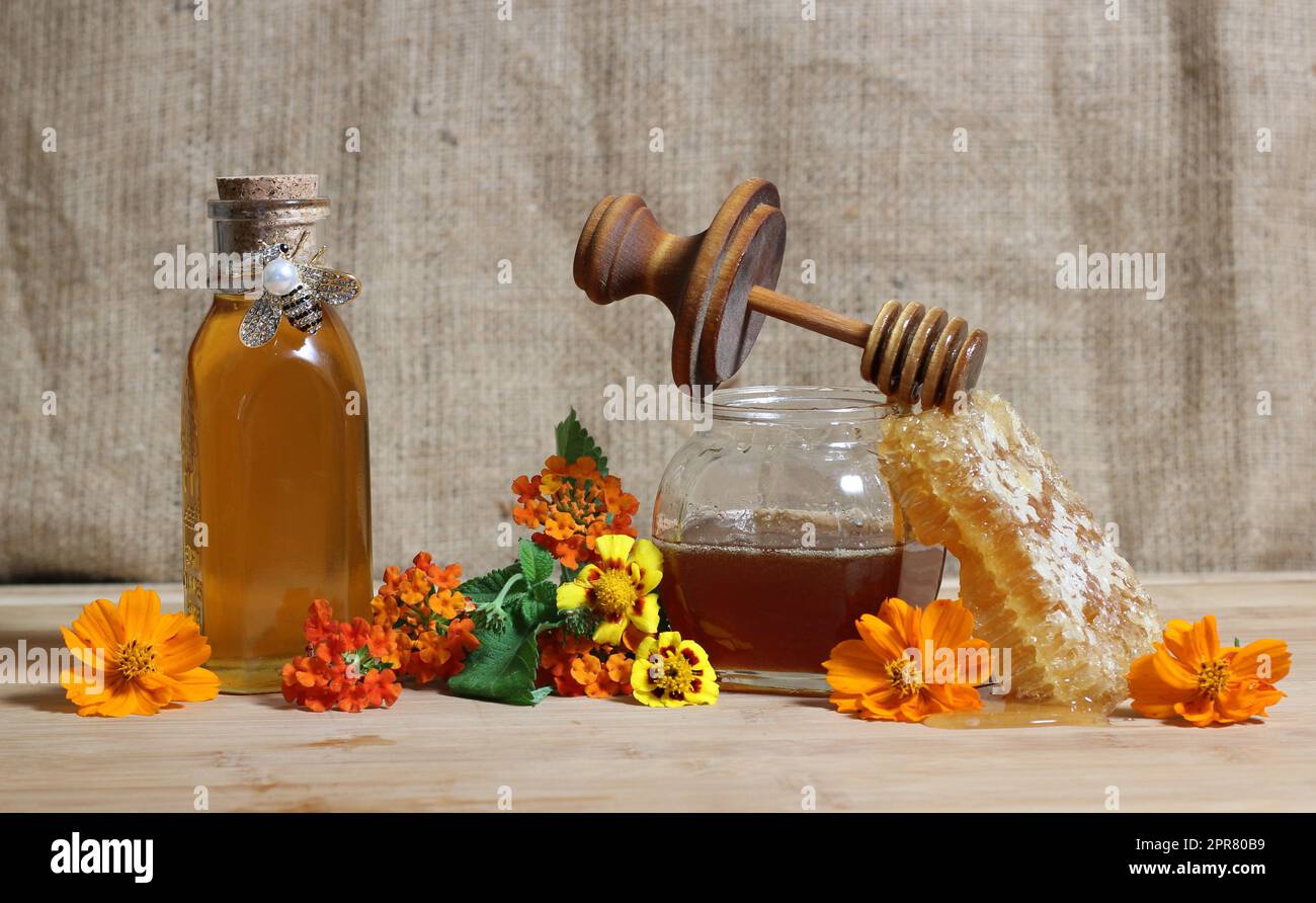 Frischer Honig mit Honigwaben und Blumen in rustikaler Küche Stockfoto