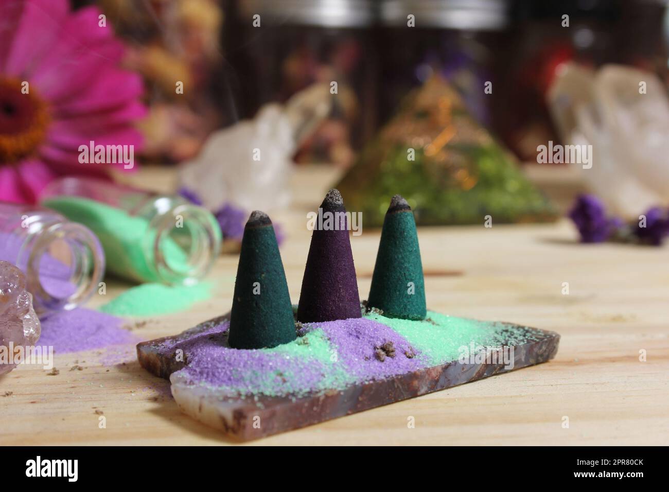 Räucherstäbchen auf Steinplatte mit Kristallen und Blumen Stockfoto