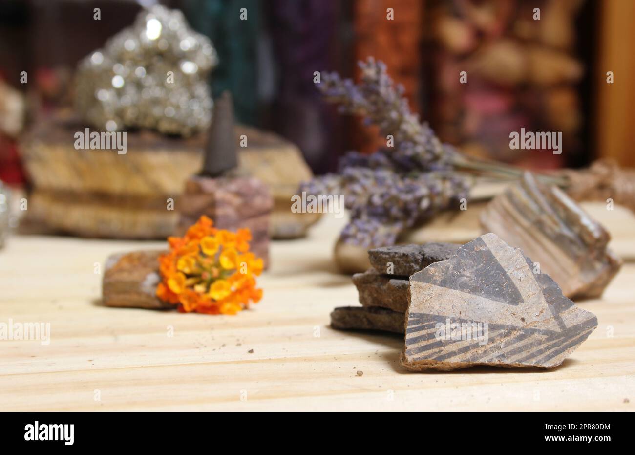 Alte Keramikstücke der Ureinwohner mit Kristallen und Blumen auf dem Meditationstisch Stockfoto