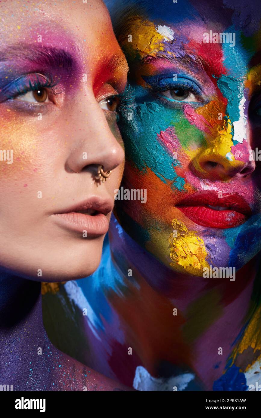Das Leben ist nicht nur schwarz-weiß. Studioaufnahme von zwei jungen Frauen, die mit mehrfarbiger Farbe auf ihrem Gesicht posieren. Stockfoto