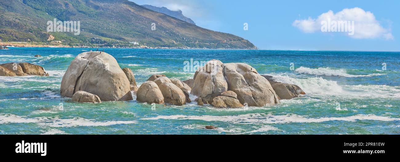 Meereslandschaft von Camps Bay Beach, Table Mountain National Park, Kapstadt, Südafrika. Ruhige, malerische Meereslandschaft mit Felsen und Wellen an einem blauen Horizont. Atemberaubendes türkisfarbenes Wasser an der Küste Stockfoto