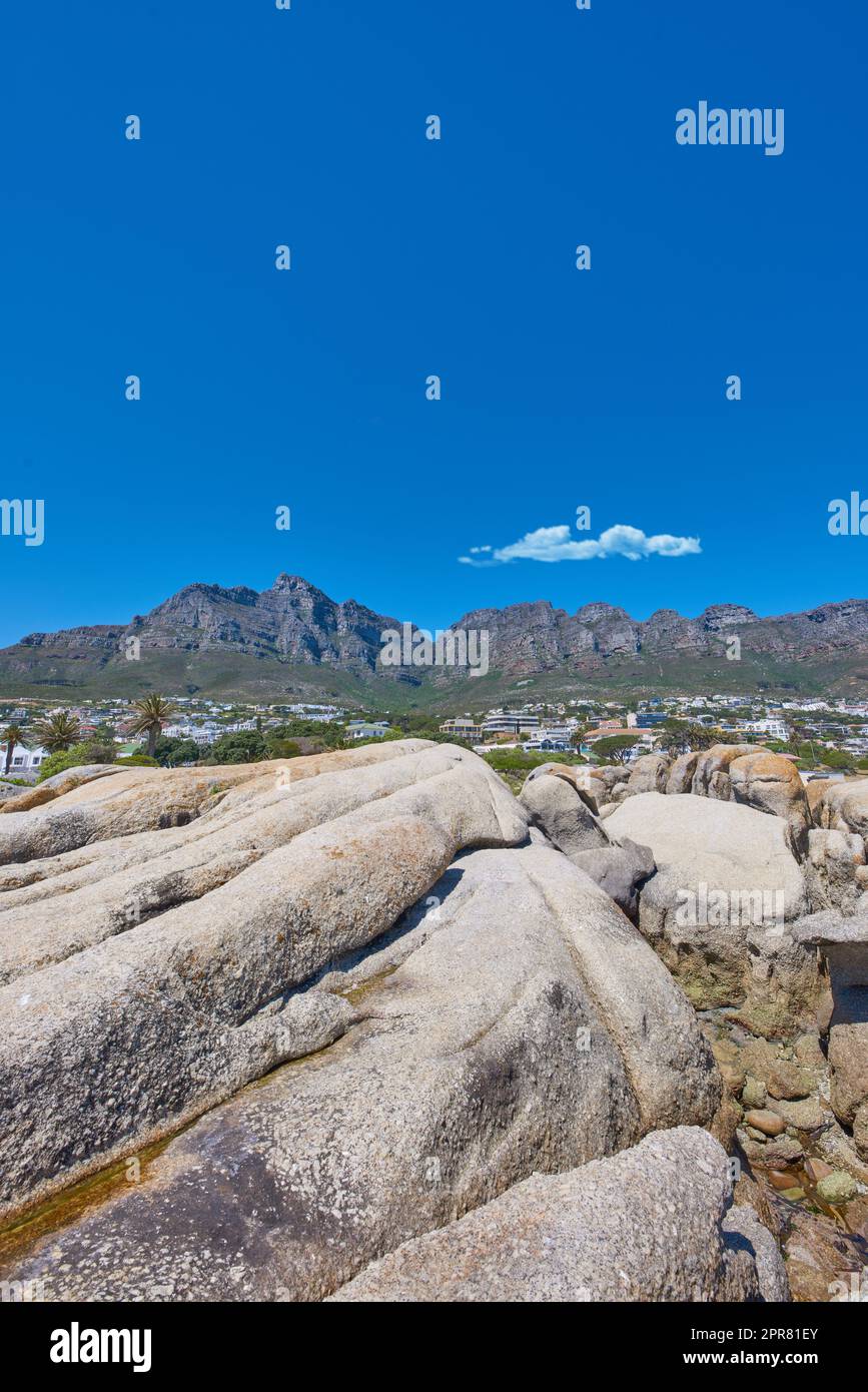 Blick aus flachem Winkel auf die Twelve Apostles Gebirgskette in Südafrika vor blauem Himmel. Nahaufnahme der felsigen Landschaft unter einer beliebten Touristenattraktion. Abgelegener Reiseort in der Nähe des Tafelbergs Stockfoto