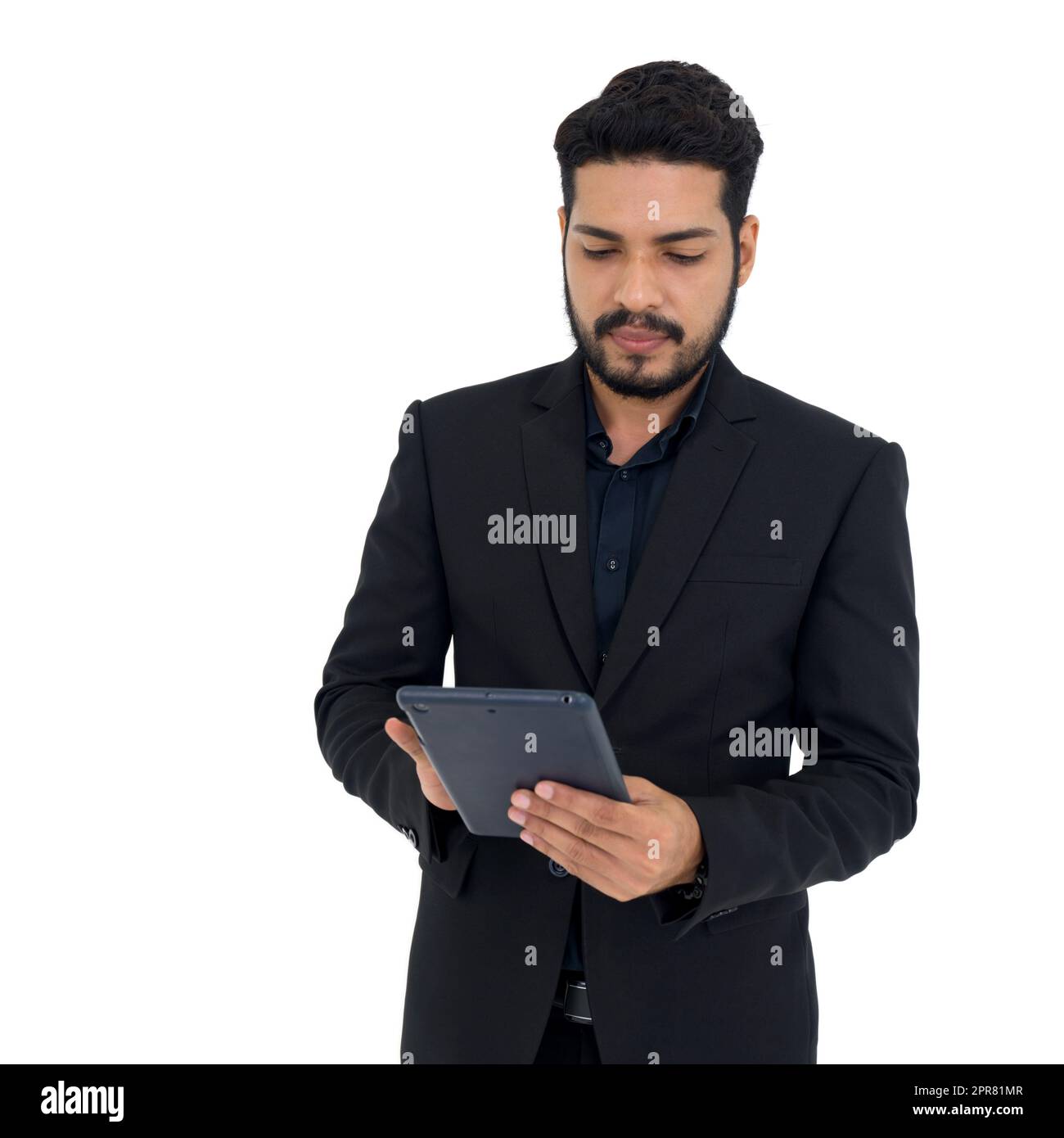 Junger Geschäftsmann mit Schnurrbart und Bart in schwarzem Anzug, der auf einem Tablet-Computer tippt. Porträt auf weißem Hintergrund mit Studiobeleuchtung. Isoliert Stockfoto