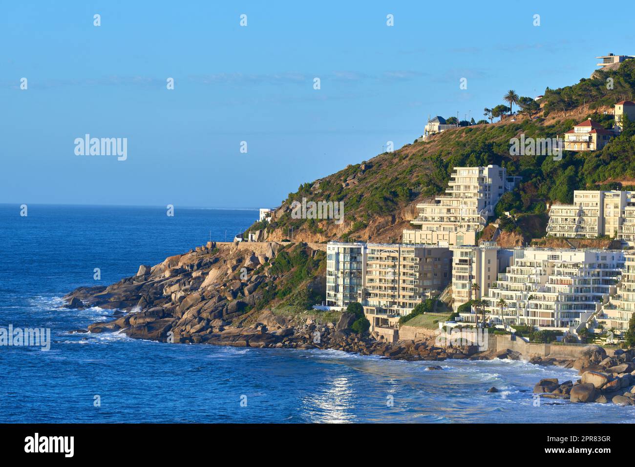Clifton, Kapstadt, Südafrika Panorama Meereslandschaft mit klarem blauen Himmel, Hotels und Apartmentgebäude im Hintergrund. Wohnungsbau mit Blick auf die wunderschöne Halbinsel des blauen Ozeans Stockfoto