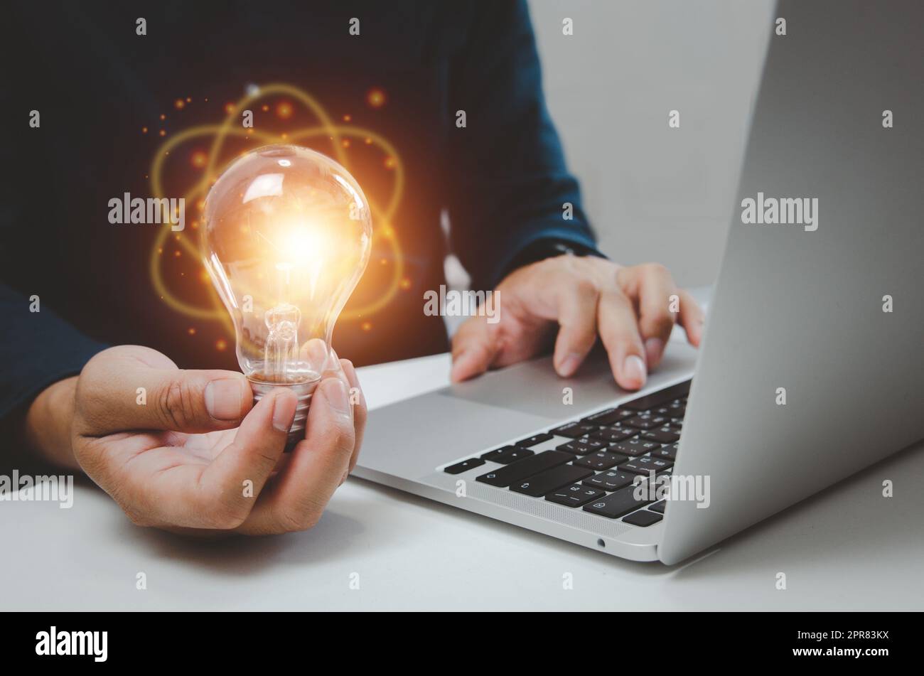 Hand Mann hält Glühbirne Licht Idee Kreativität Inspiration und mit Computer-Laptop auf dem Schreibtisch. Stockfoto