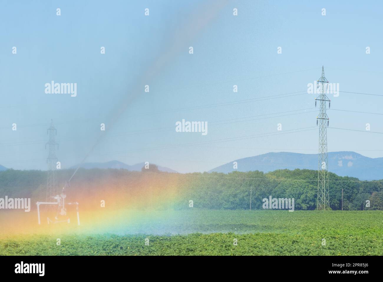 Bewässerungsmaschine auf einem grünen Feld mit einem Regenbogen Stockfoto