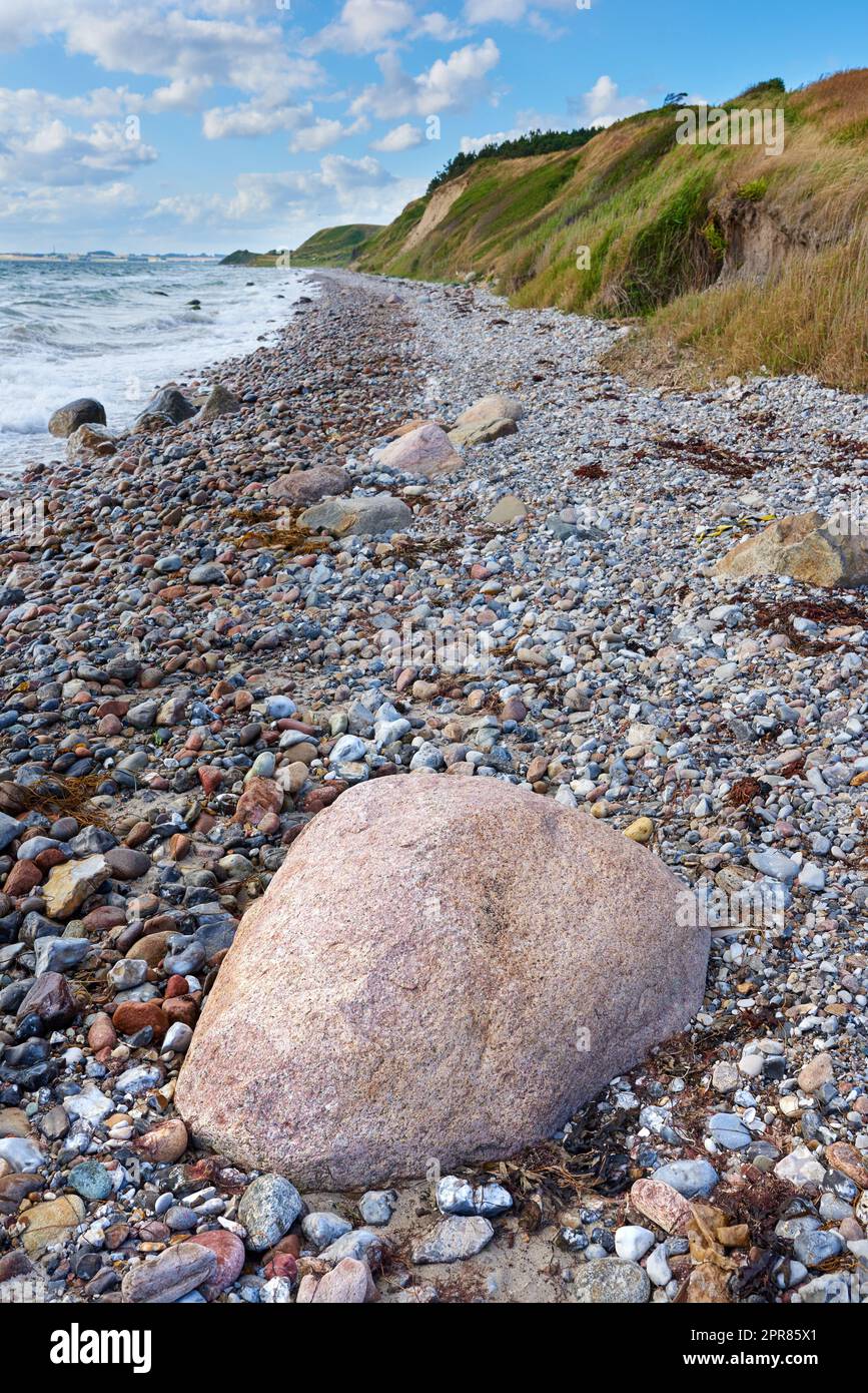 Küste von Kattegat - Helgenaes, Dänemark. Meereswellen, die auf leere Steine am Strand waschten. Ruhiges, friedliches Paradies der Sommerlandschaft und des Himmels für einen entspannten Urlaub im Ausland oder einen Urlaub auf Reisen Stockfoto