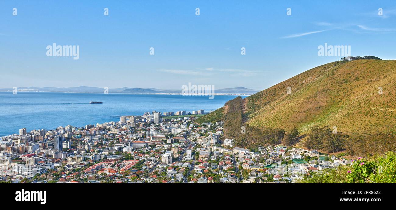 Panoramaaufnahme einer Küstenstadt am Fuße eines Hügels. Das zentrale Geschäftsviertel von Kapstadt, Südafrika, Ein malerischer Horizont, der sowohl Land als auch Stadt zeigt, sowie ein Geschäftsviertel Stockfoto