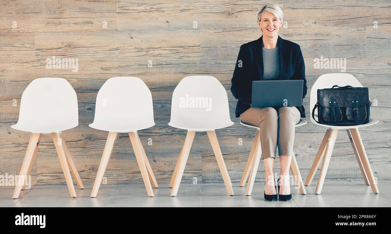 Harte Arbeit bedeutet alles. Aufnahme einer reifen Geschäftsfrau, die einen Laptop benutzt, während sie in einem Büro ansteht. Stockfoto