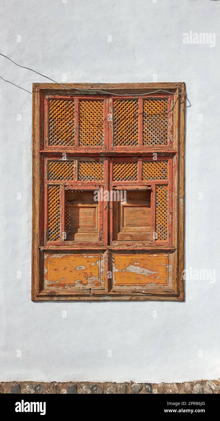 Architektur einer alten grauen Wand mit einem rostigen Metallfenster draußen. Äußere Texturdetails eines alten, rustikalen Wohngebäudes mit alten geschlossenen Holzfenstern, die in Santa Cruz de La Palma entdeckt wurden Stockfoto