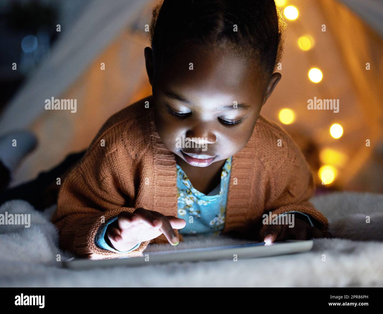 Ein kleines Gerät voller großer Lebensstunden. Ein entzückendes kleines Mädchen, das ein digitales Tablet während der Schlafenszeit zu Hause benutzt. Stockfoto