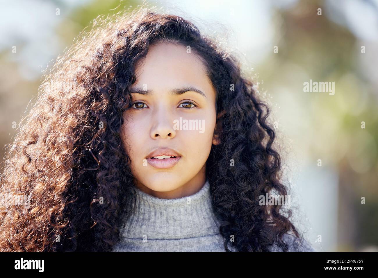 Das Leben soll nicht so ernst genommen werden. Eine attraktive junge Frau, die tagsüber alleine draußen steht. Stockfoto