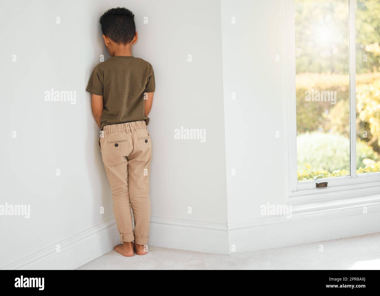 Es gibt verschiedene Möglichkeiten, ein Kind zu disziplinieren. Aufnahme eines kleinen Jungen, der zu Hause in einer Ecke steht. Stockfoto