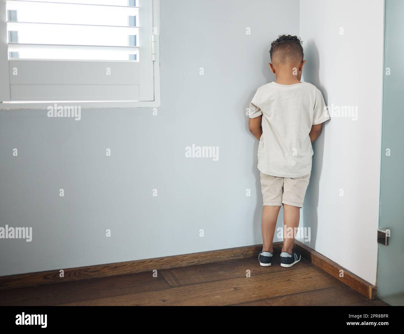 Er hasst es nicht, seinen Weg zu finden. Aufnahme eines unerkennbaren kleinen Jungen, der zur Wand zeigt und als Strafe in einem Zimmer zu Hause eingesetzt wird. Stockfoto
