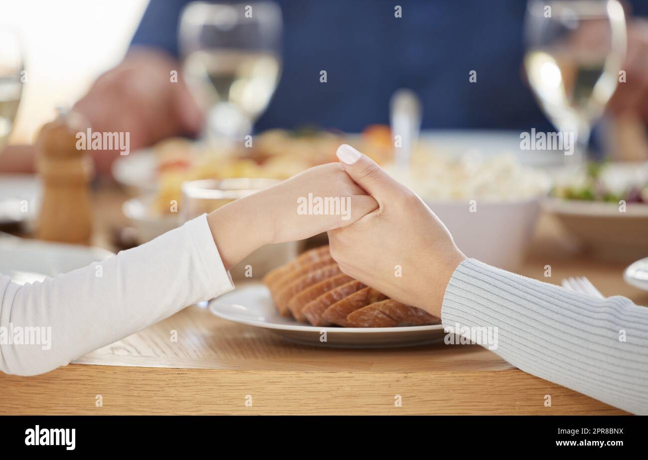 Vielen Dank, dass Sie an meiner Seite sind. Zwei unkenntliche Menschen halten sich zu Hause am Esstisch die Hände. Stockfoto