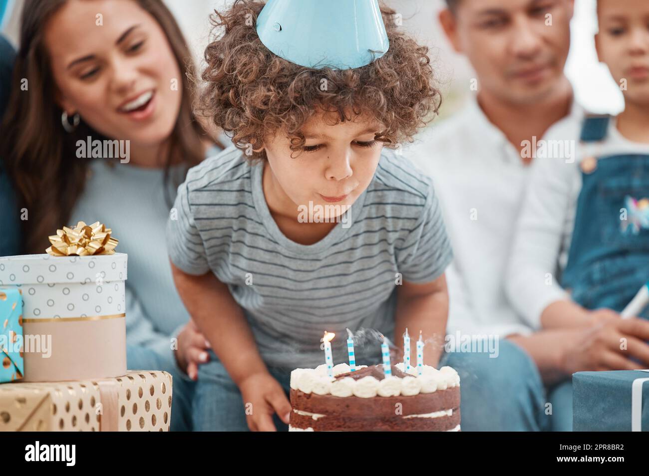Große Jungen blasen alle ihre Kerzen aus. Ein entzückender kleiner Junge feiert einen Geburtstag mit seiner Familie zu Hause. Stockfoto