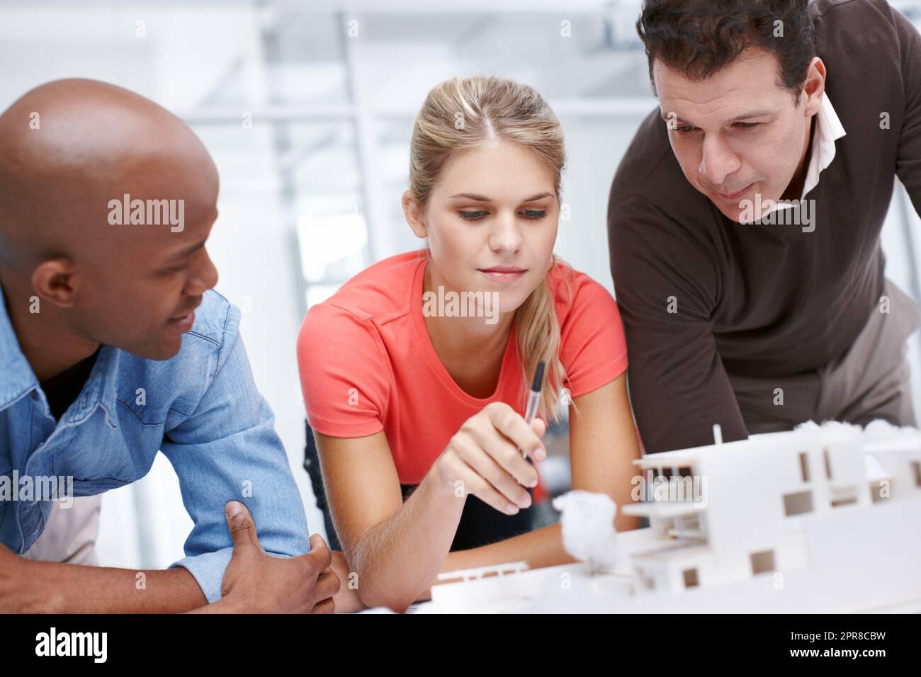 Wir brauchen etwas Inspiration Ein Team von Architekten, die gemeinsam an einem Architekturmodell arbeiten. Stockfoto