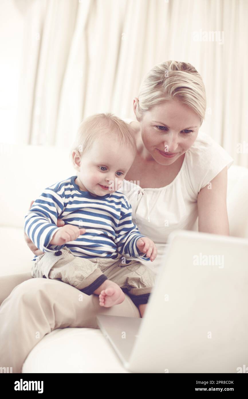 Teilen Sie die Wunder der modernen Technologie zusammen. Eine attraktive junge Mutter zeigt ihrem neugierigen Baby einen Laptop. Stockfoto