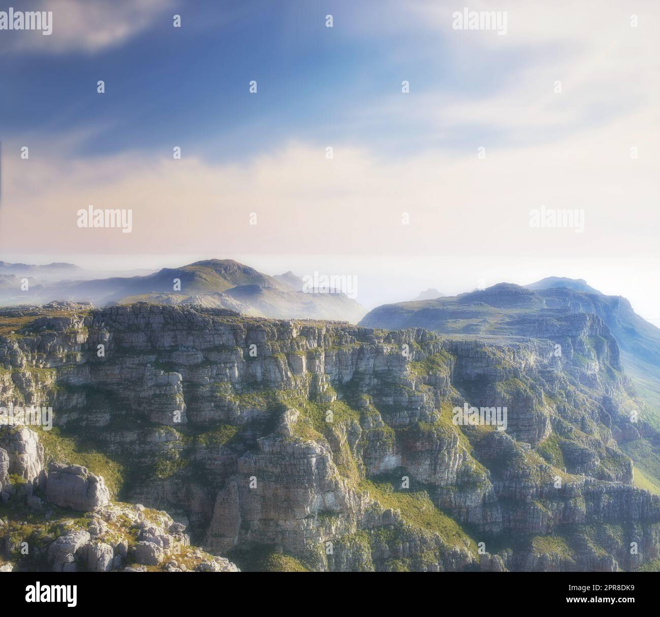 Kopieren Sie Platz mit malerischer Landschaft aus Wolken am Himmel, die den Gipfel des Tafelbergs in Kapstadt an einem nebligen Morgen bedecken. Fantastische Aussicht von hoch über einem felsigen Tal nach einem Gipfel auf einem Berg Stockfoto