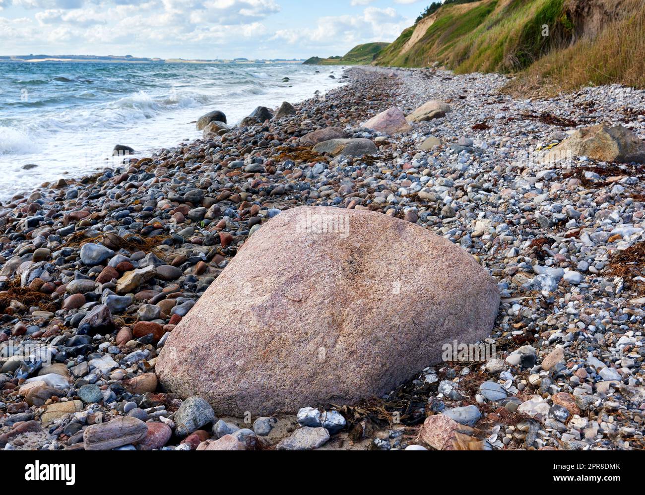 Küste von Kattegat - Helgenaes, Dänemark. Meereswellen, die auf leere Steine am Strand waschten. Ruhiges, friedliches Paradies der Sommerlandschaft und des Himmels für einen entspannten Urlaub im Ausland oder einen Urlaub auf Reisen Stockfoto