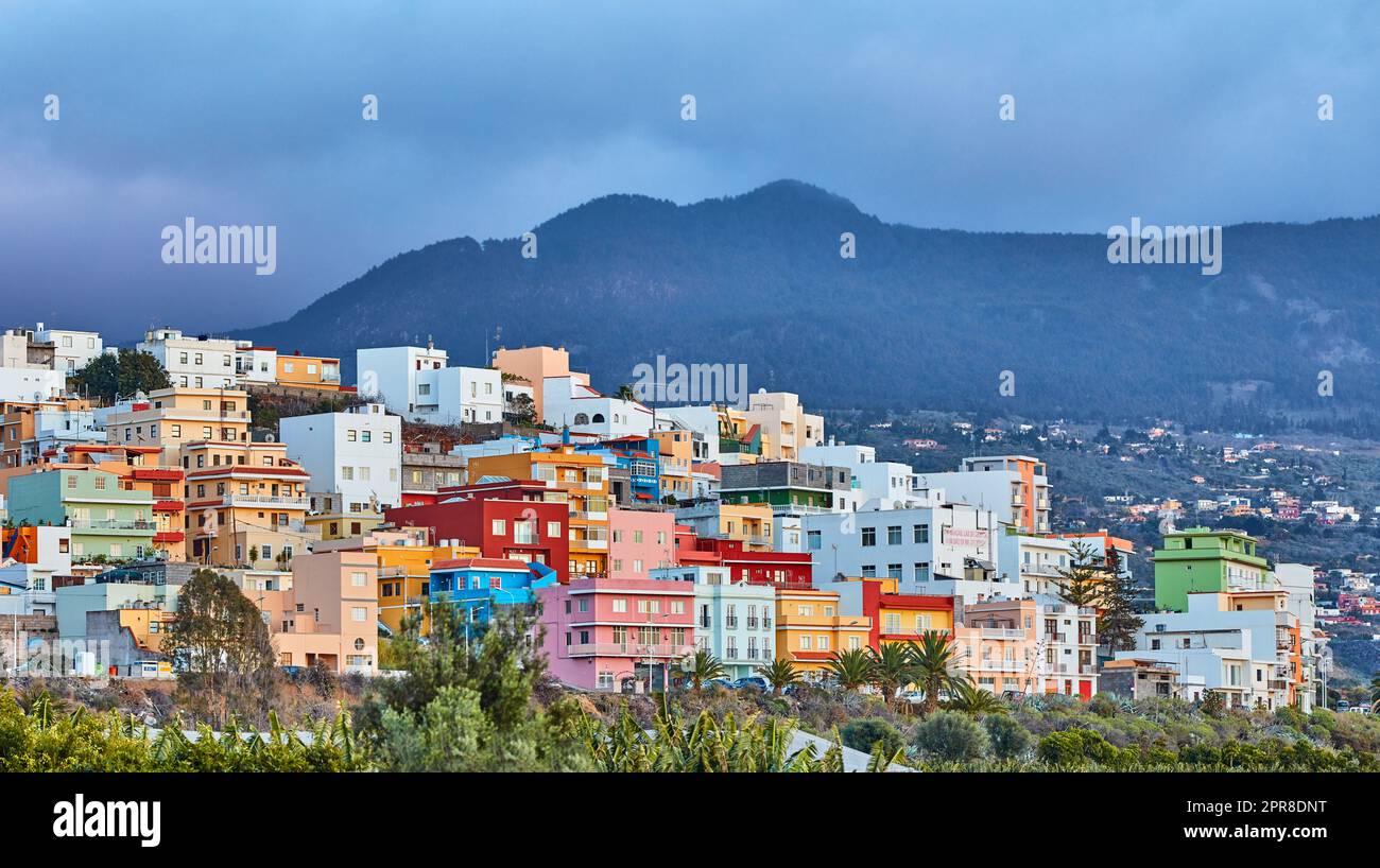Farbenfrohe Gebäude in Santa Cruz de La Palma mit Kopierbereich. Wunderschöne Stadtlandschaft mit hellen Farben, Bergen und bedeckten Wolken. Ein lebhaftes Urlaubs- oder Urlaubsziel am Hang Stockfoto