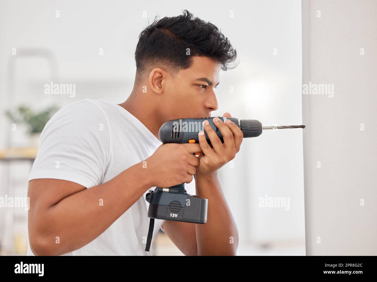 Hier brauche ich das Loch. Aufnahme eines Mannes mit einem Akku-Bohrer an einer Wand. Stockfoto