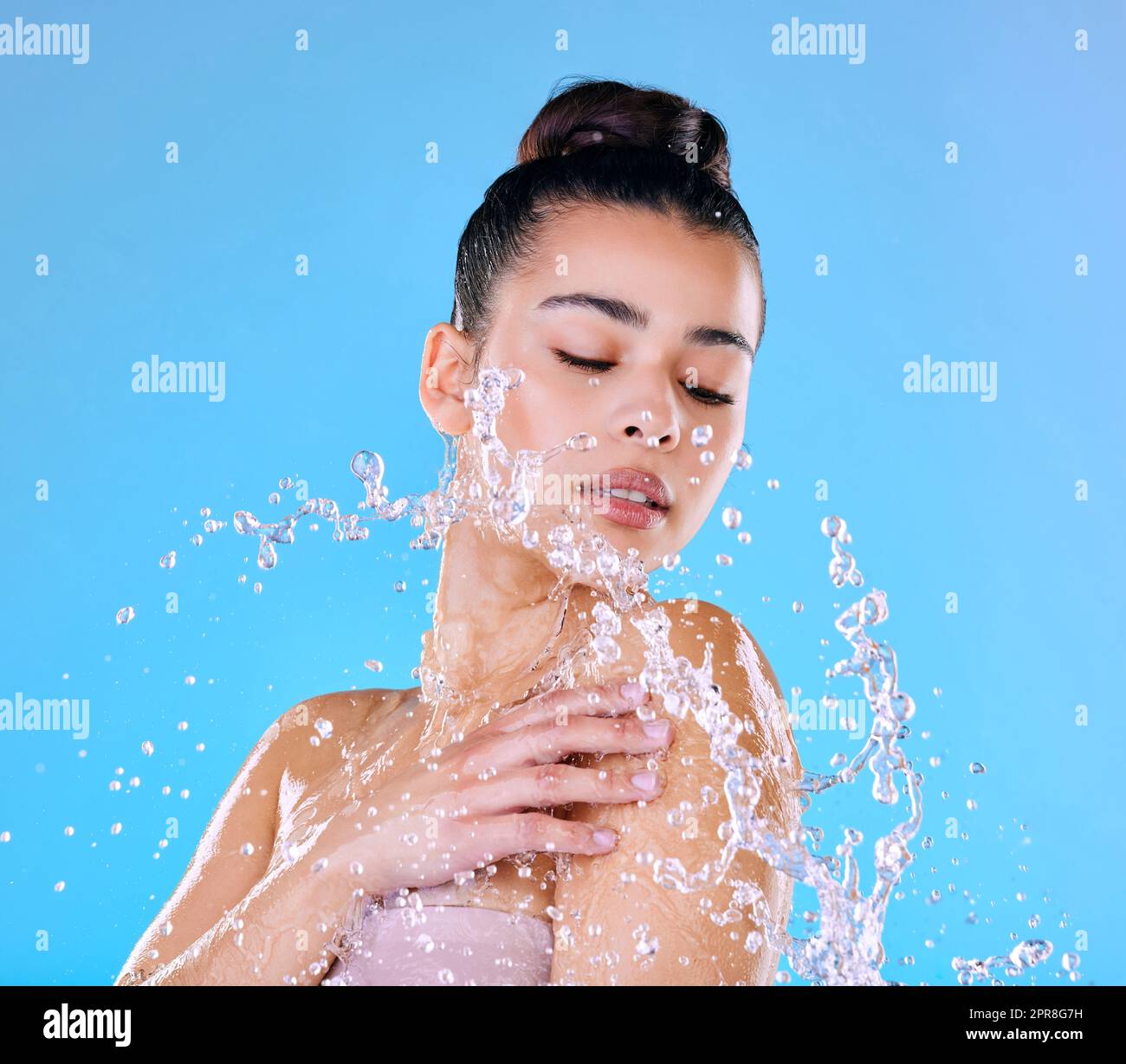Ich Zeit. Aufnahme einer schönen jungen Frau, die vor blauem Hintergrund mit Wasser bespritzt wurde. Stockfoto