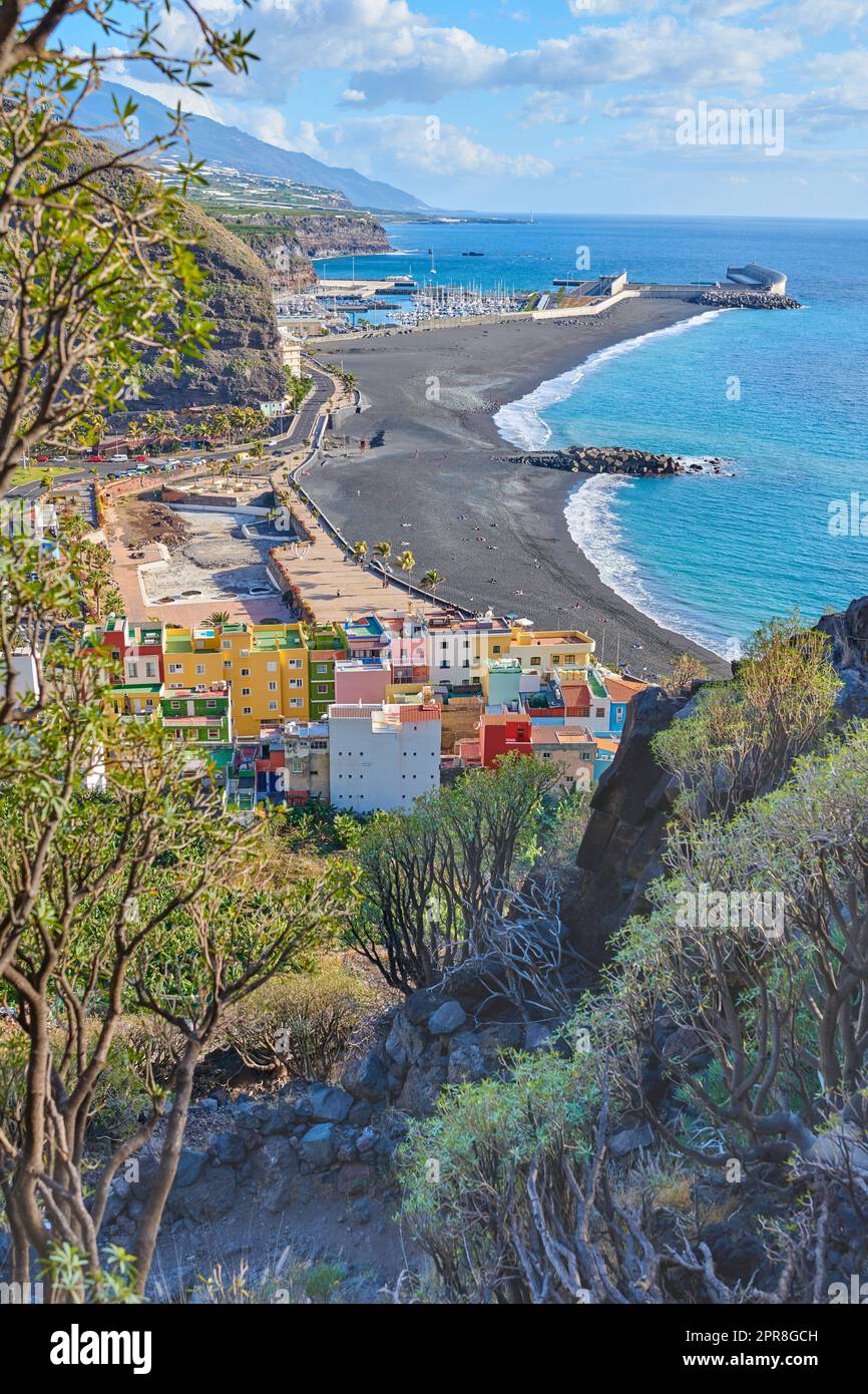 Landschaft einer Meeresküste mit schwarzem Sandstrand auf Puerto de Tazacorte. Farbenfrohe Stadthäuser oder Ferienunterkünfte in der Nähe des Meeres in einem wunderschönen Reiseziel, La Palma, Spanien Stockfoto