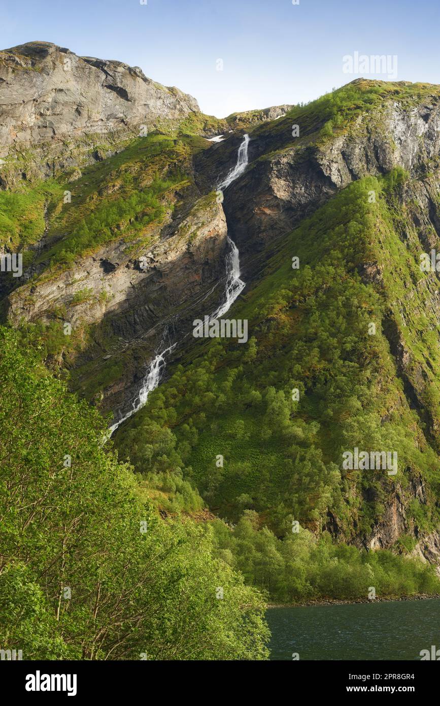 Bergquellenwasser fließt durch ein Dschungel auf einer Insel, Natur in ihrer reinsten Form. Wunderschöne Landschaft mit sauberem Flusswasser, das an einem Sommertag in der Natur einen felsigen Hügel hinunterfließt. Stockfoto