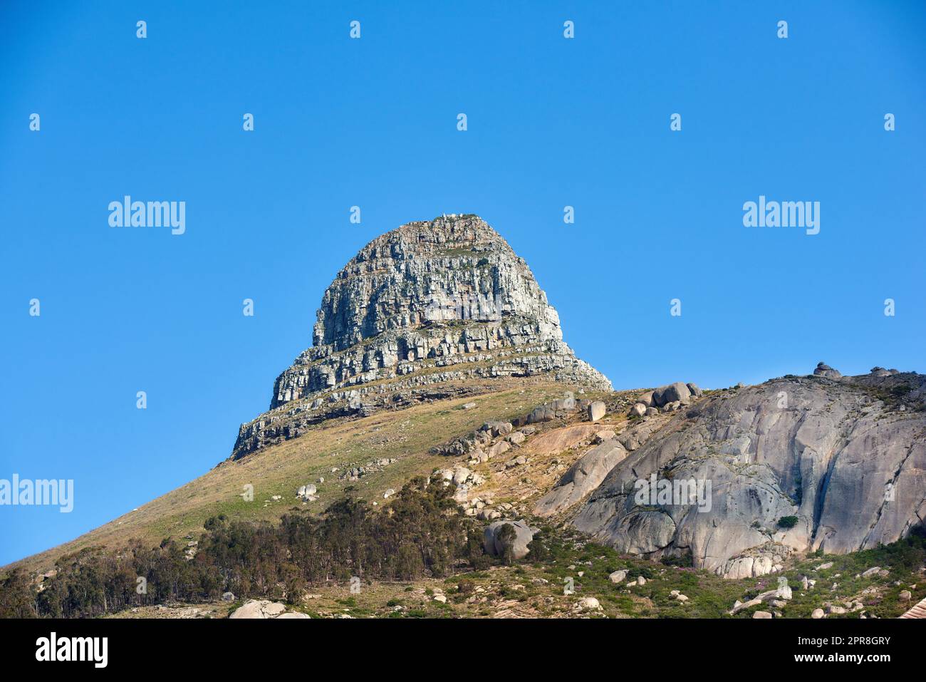 Malerische Landschaft mit blauem Himmel über dem Gipfel des Tafelbergs in Kapstadt von unten mit viel Platz. Wunderschöne Aussicht auf Pflanzen und Bäume rund um eine beliebte Touristenattraktion und ein Naturdenkmal Stockfoto