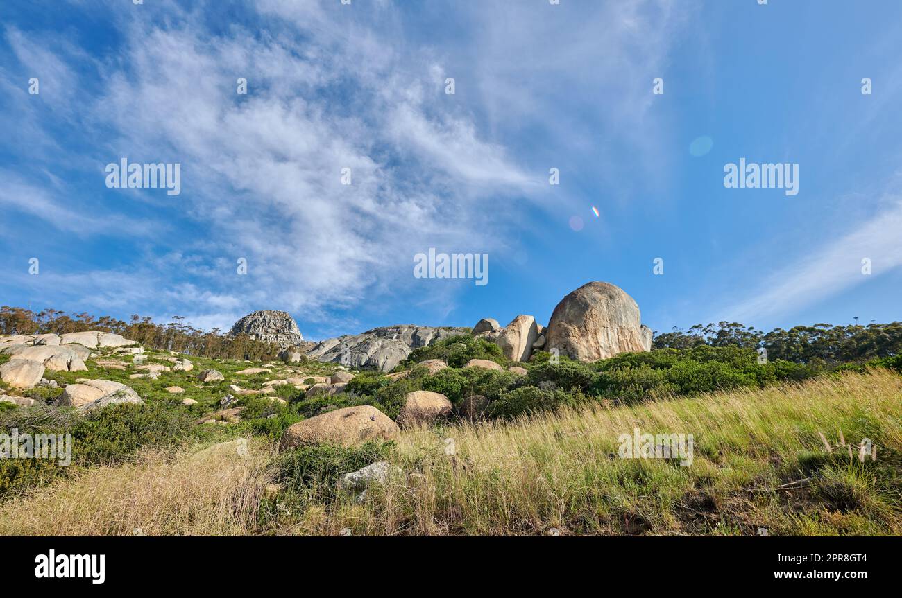 Copyspace mit malerischem Blick auf den Lions Head Mountain in Kapstadt, Südafrika, vor einem wolkigen blauen Himmelshintergrund. Wunderschöner Panoramablick auf ein berühmtes Reiseziel mit üppigen Pflanzen und felsiger Landschaft Stockfoto
