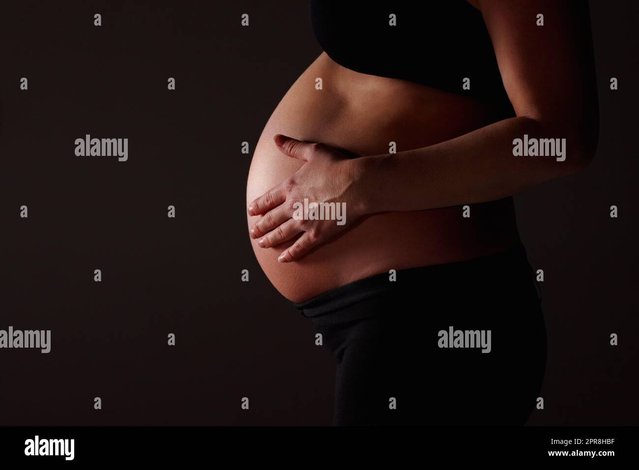 Schwanger Frau erwartet ein Baby gegen schwarz - Copyspace. Mittelteil einer Schwangeren, die ein Baby gegen Schwarz erwartet - Copyspace. Stockfoto