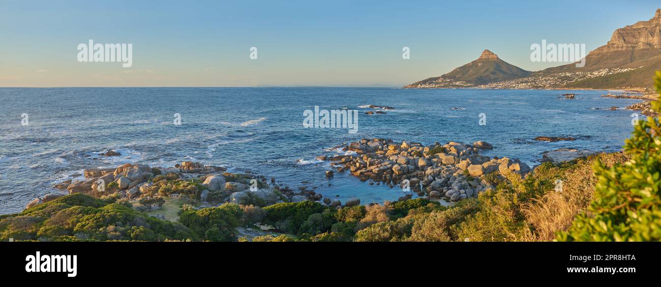 Panorama der wunderschönen Landschaft mit Blick auf das Meer und Lions Head in Kapstadt bei Sonnenuntergang. Banner eines friedlichen Morgens mit Gipfeln und Landschaft in Südafrika, ruhige, ruhige und ruhige Natur Stockfoto