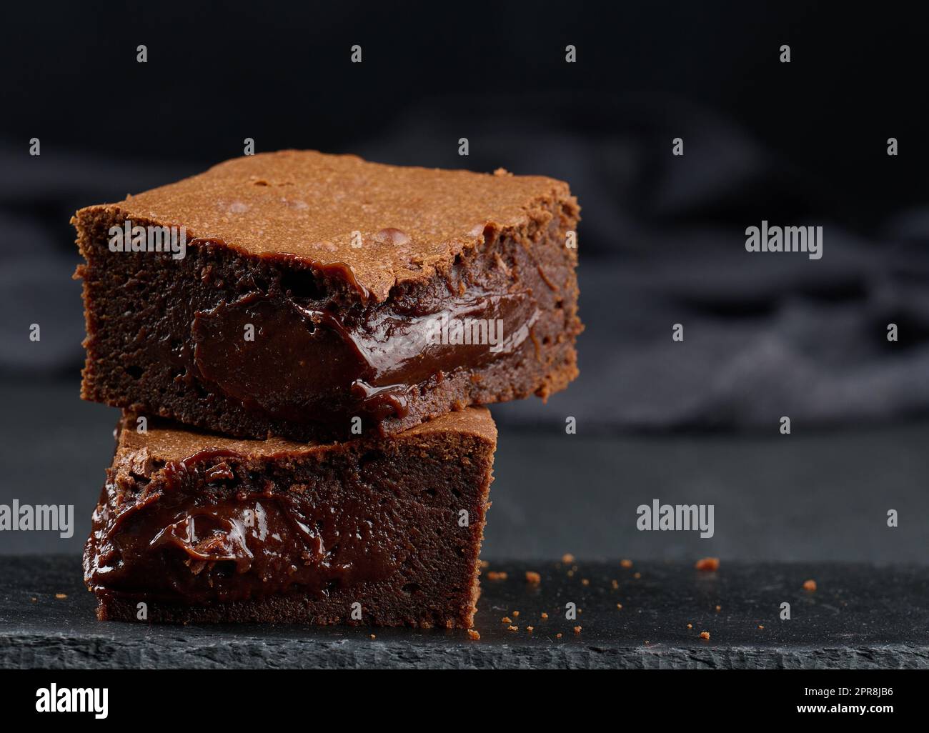 Gebackene Brownie-Schokoladenstückchen auf schwarzem Tisch, köstliches Dessert Stockfoto