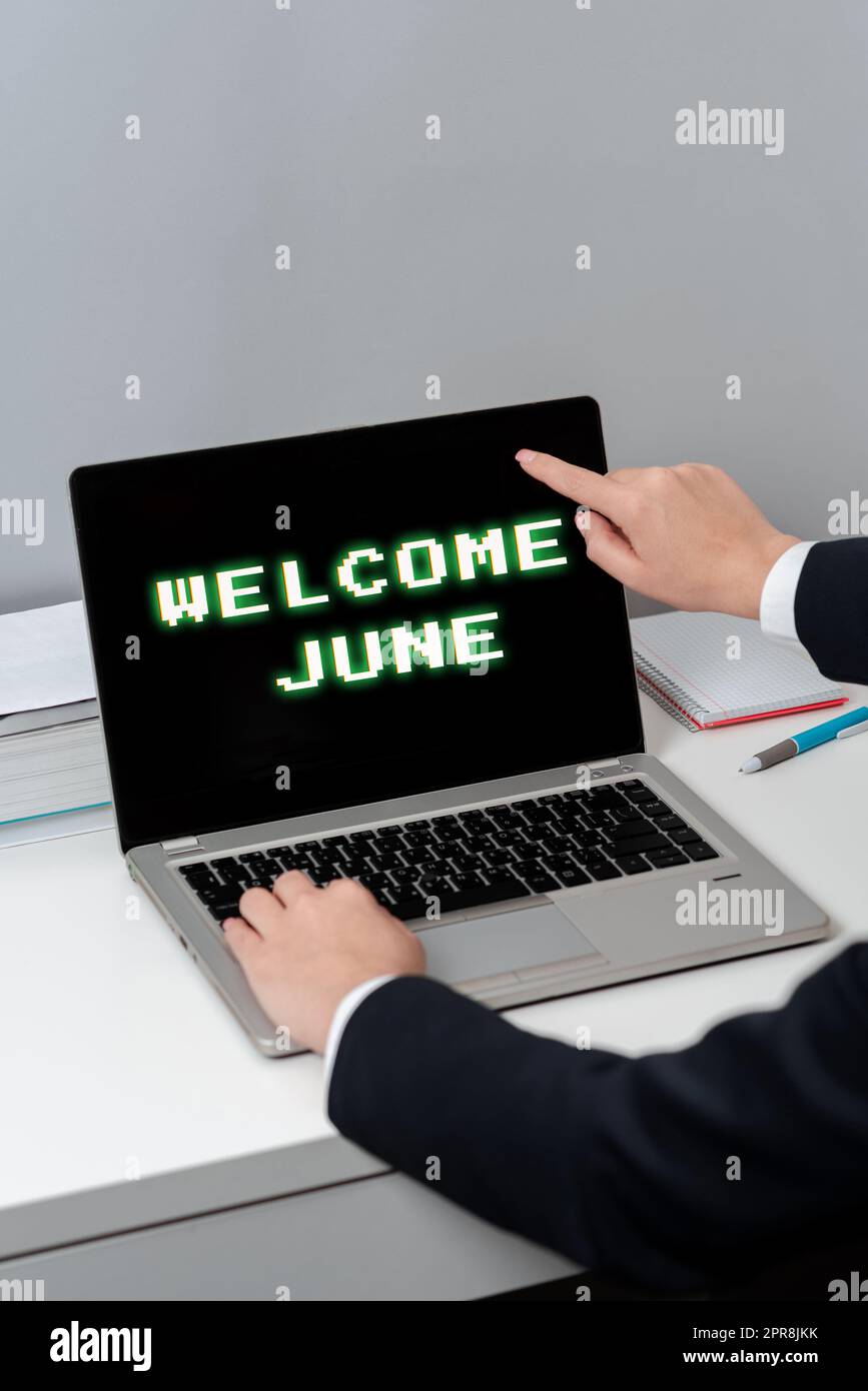 Inspiration mit Schild „Welcome June“. Konzept Bedeutung Kalender Sechster Monat Zweites Quartal dreißig Tage Grüße Frau schreibt Updates auf Laptop und zeigt mit einem Finger auf neue Ideen. Stockfoto