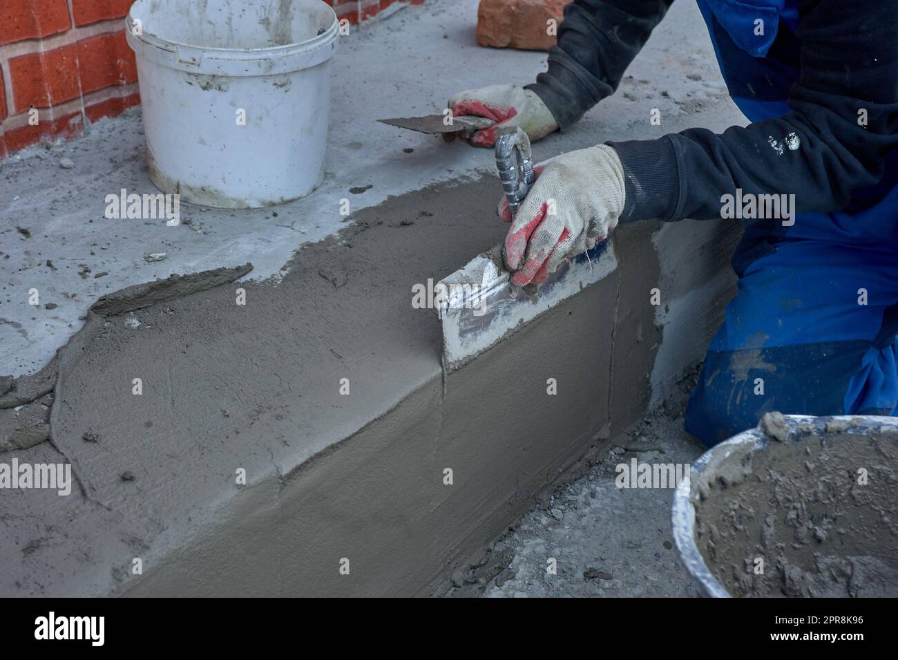 Ein Arbeiter verwendet einen Spachtel, um das Zementgemisch entlang der Rampe zu verteilen Stockfoto