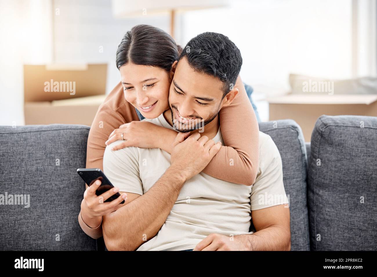 Wir können alles, was wir brauchen, online einkaufen. Aufnahme eines jungen Paares, das ein Mobiltelefon benutzte, während es in ein Haus umzog. Stockfoto