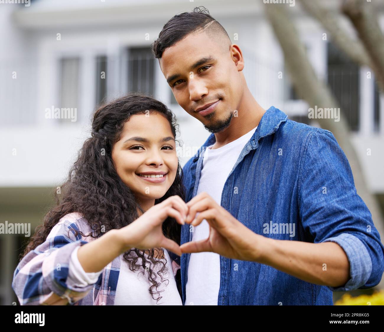 Liebe ist hier, um zu bleiben. Aufnahme eines jungen Paares, das eine Herzgeste mit den Händen im Garten macht. Stockfoto