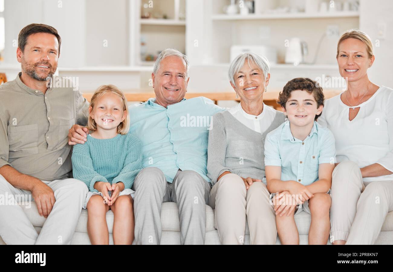 Nur eine, große, glückliche Familie. Beschnittenes Porträt von zwei entzückenden kleinen Kindern, die zu Hause mit ihren Eltern und Großeltern auf dem Sofa sitzen. Stockfoto