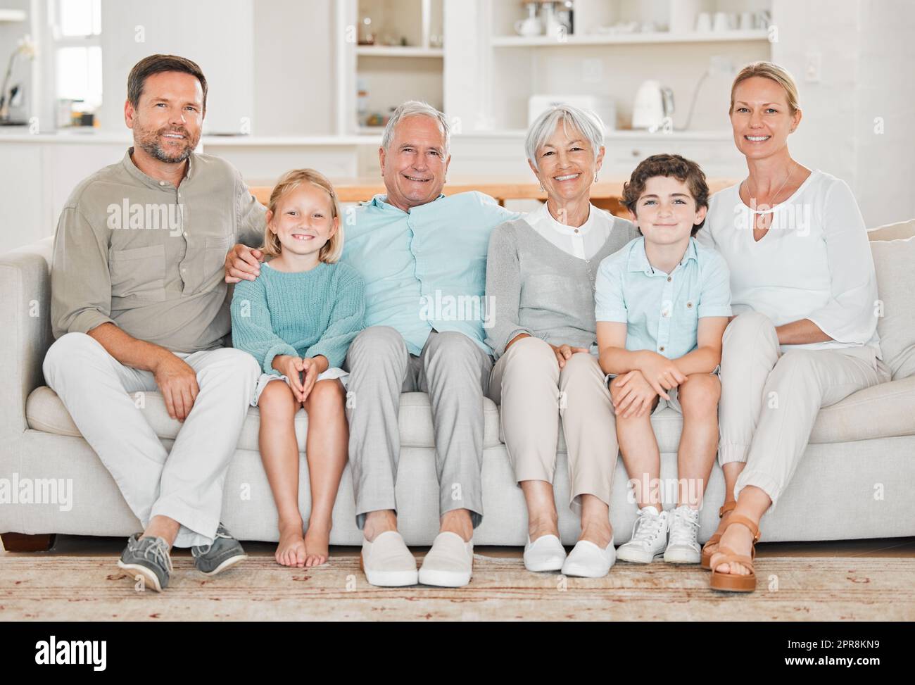 Familie ist alles für uns. Porträt zweier entzückender kleiner Kinder, die zu Hause mit ihren Eltern und Großeltern auf dem Sofa sitzen. Stockfoto