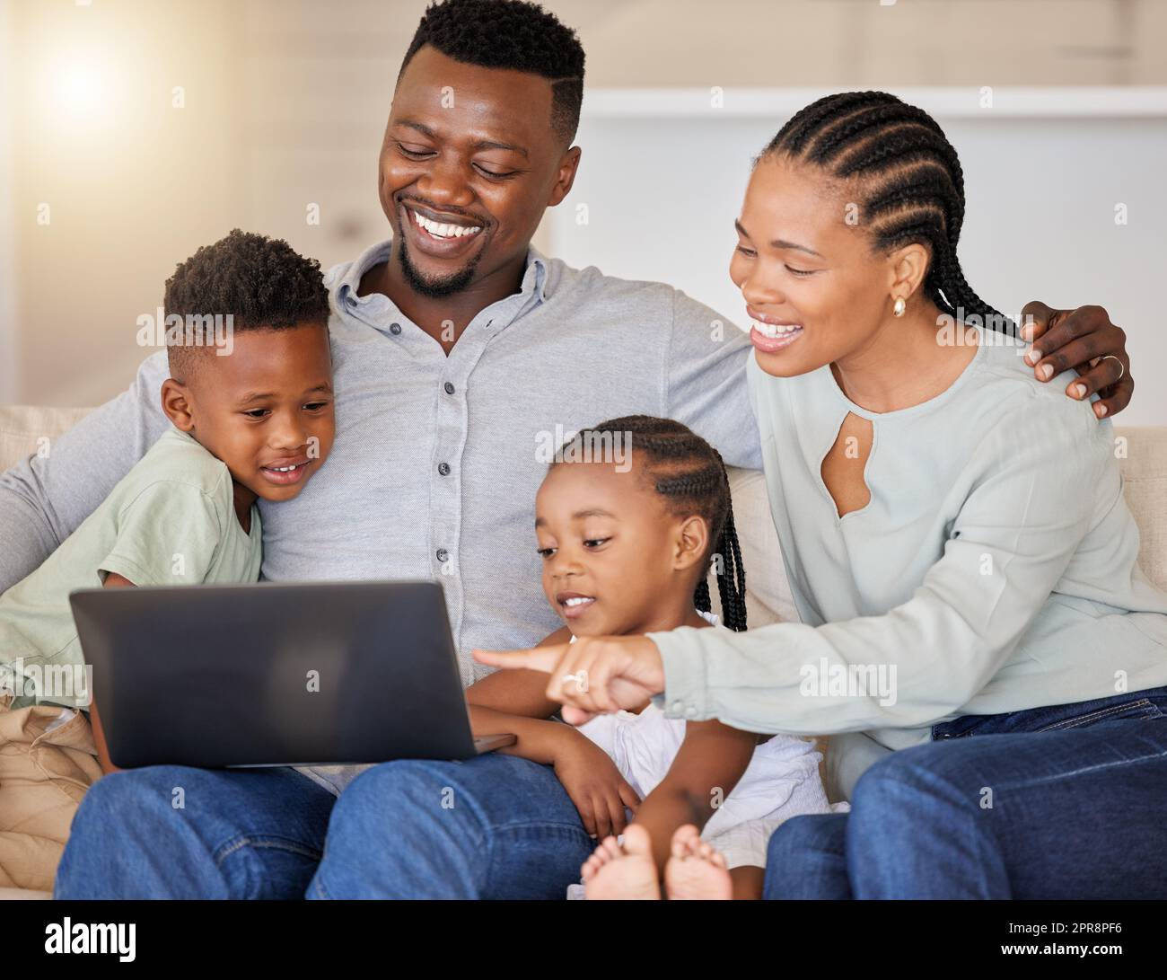 Wir lieben diesen Film. Eine junge afrikanische Familie schaut sich zusammen Filme auf einem Laptop an. Stockfoto