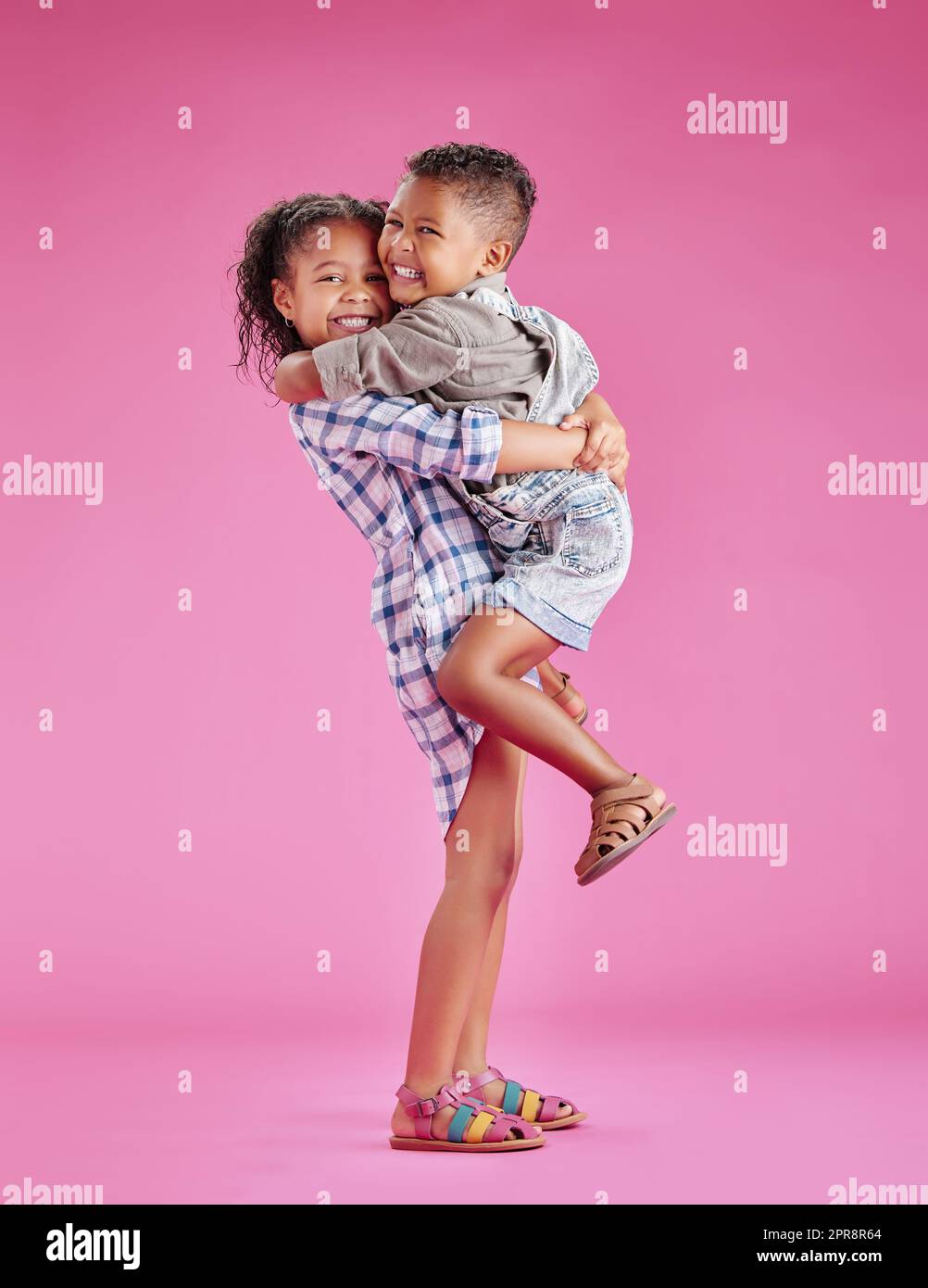 Zwei Kinder posieren nur und sind liebevoll vor einem rosa Copyspace Hintergrund. Afroamerikanische Mischrassengeschwister, die sich in einem Studio zusammenbinden Stockfoto