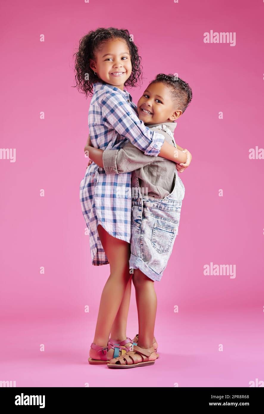 Zwei Kinder posieren nur und sind liebevoll vor einem rosa Copyspace Hintergrund. Afroamerikanische Mischrassengeschwister, die sich in einem Studio zusammenbinden Stockfoto